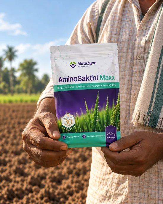 Farmer holding an AminoSakthi Maxx pouch in front of a tilled field lined with palm trees